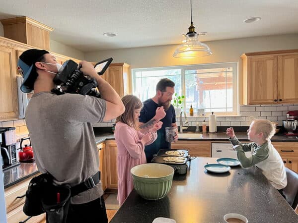 Behind the scenes of a public health vaccination video showing a family in a kitchen being filmed during the Oregon Health Authority campaign