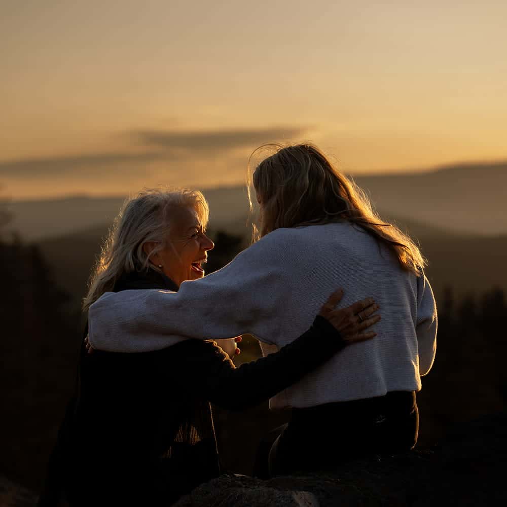 Two people sitting together at sunset in the mountains